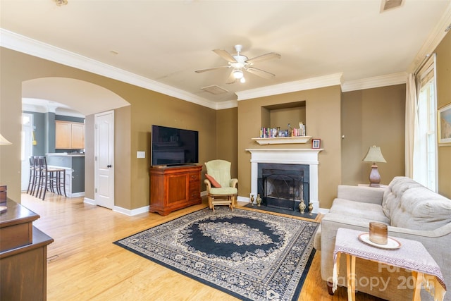 123 Singleton Rd, Mooresville, NC 28117 - living room featuring a fireplace with raised hearth, a ceiling fan, arched walkways, wood finished floors, and crown molding