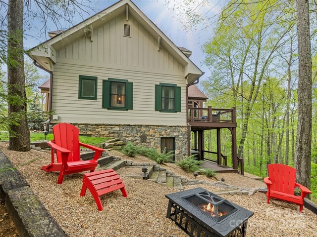 62 Blair Athel Pt, Waynesville, NC 28786 - rear view of house featuring an outdoor fire pit, board and batten siding, a wooden deck, and stone siding