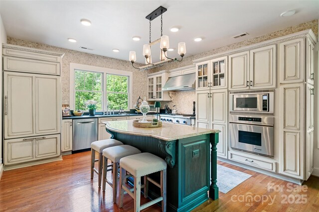 62 Blair Athel Pt, Waynesville, NC 28786 - kitchen featuring appliances with stainless steel finishes, range hood, a chandelier, light wood finished floors, and a kitchen island