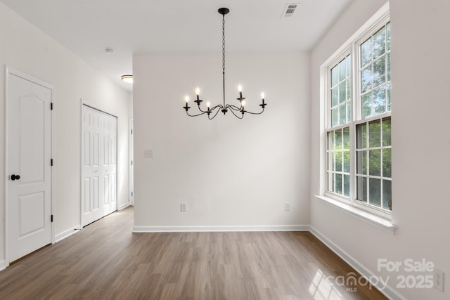 5529 Seths Dr, Charlotte, NC 28269 - unfurnished dining area featuring wood finished floors, a chandelier, plenty of natural light, and baseboards