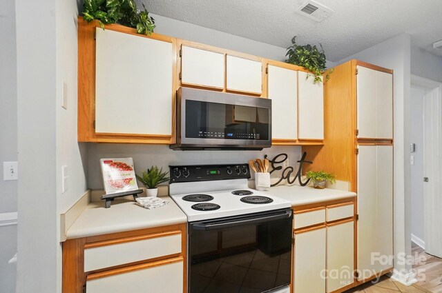 317 Cedarcroft Dr, Mooresville, NC 28115 - kitchen with stainless steel microwave, range with electric stovetop, light countertops, light tile patterned flooring, and a textured ceiling