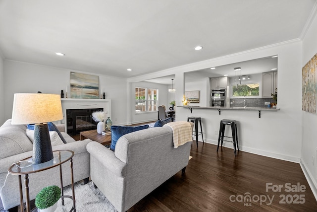 917 Dent Ct, Charlotte, NC 28210 - living room featuring dark wood-style flooring, a glass covered fireplace, recessed lighting, and crown molding