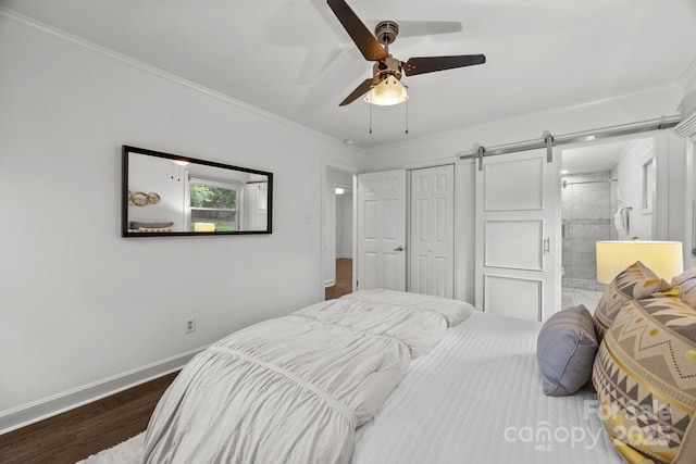 917 Dent Ct, Charlotte, NC 28210 - bedroom featuring a barn door, dark wood finished floors, a closet, crown molding, and ensuite bathroom