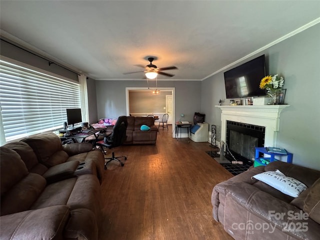 living area with wood finished floors, ceiling fan, a tile fireplace, and ornamental molding