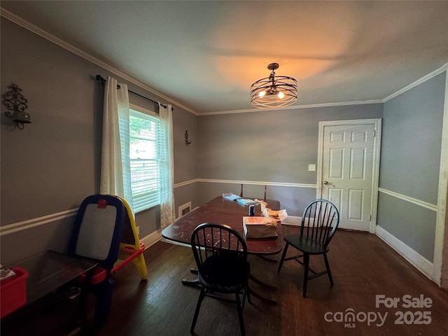 dining area featuring ornamental molding, wood finished floors, baseboards, and a chandelier