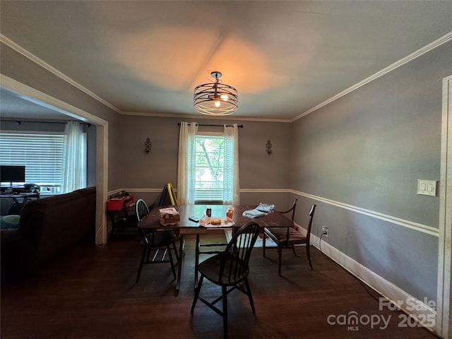 dining room with wood finished floors, ornamental molding, and baseboards