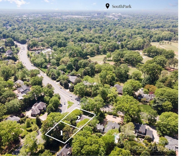 aerial view of property and surrounding area featuring property boundaries highlighted and a heavily wooded area