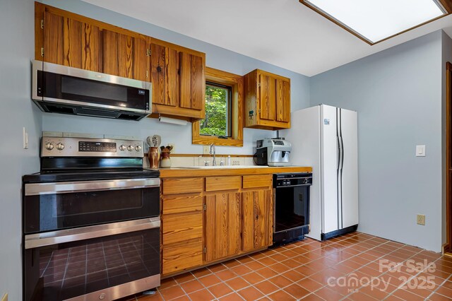 214 Laurel Mountain Trl, Saluda, NC 28773 - kitchen featuring stainless steel appliances, brown cabinets, light countertops, tile patterned floors, and a sink