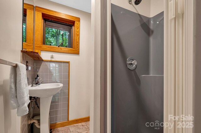 214 Laurel Mountain Trl, Saluda, NC 28773 - bathroom featuring a shower, baseboards, a sink, and backsplash