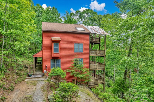 214 Laurel Mountain Trl, Saluda, NC 28773 - rustic home with a balcony, dirt driveway, and a wooden deck