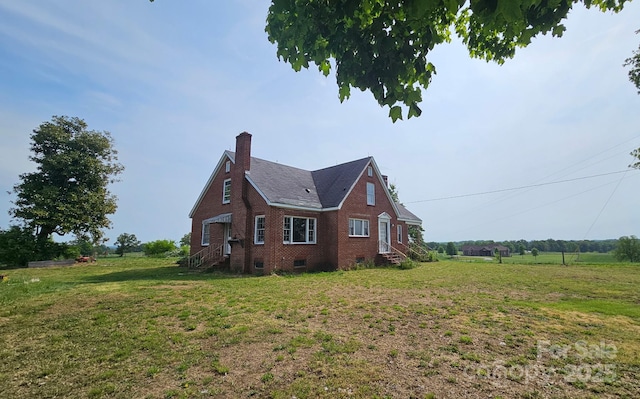 view of side of home with crawl space, brick siding, entry steps, and a yard