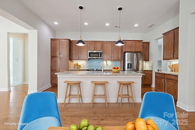 467 Granite Lake Ct, Denver, NC 28037 - kitchen with stainless steel appliances, wood finished floors, decorative backsplash, a breakfast bar area, and a center island with sink