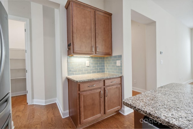 467 Granite Lake Ct, Denver, NC 28037 - kitchen featuring wood finished floors, backsplash, brown cabinets, and freestanding refrigerator