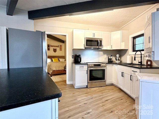 109 Beechwood Ln, Beech Mountain, NC 28604 - kitchen featuring stainless steel appliances, a sink, light wood finished floors, white cabinetry, and beam ceiling