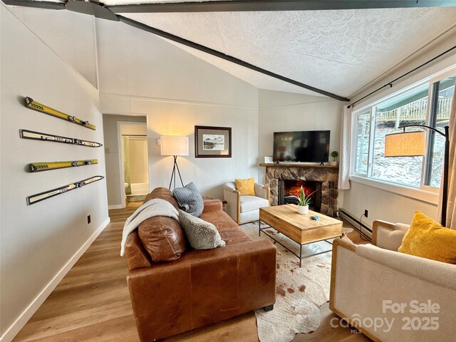 109 Beechwood Ln, Beech Mountain, NC 28604 - living area with vaulted ceiling, light wood-style floors, a baseboard heating unit, a fireplace, and baseboards