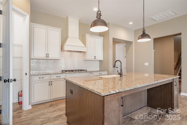 3105 Bonterra Blvd, Indian Trail, NC 28079 - kitchen featuring a sink, custom exhaust hood, light wood-style floors, white cabinets, and tasteful backsplash