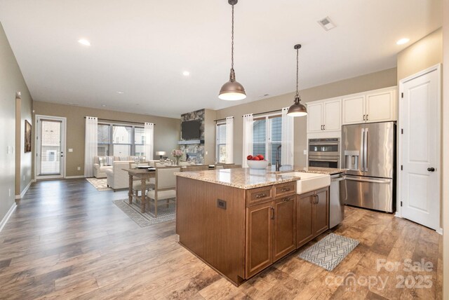 3105 Bonterra Blvd, Indian Trail, NC 28079 - kitchen with appliances with stainless steel finishes, a sink, light wood-style flooring, light stone countertops, and hanging light fixtures