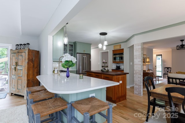 211 Southfork Dr, Belmont, NC 28012 - kitchen with appliances with stainless steel finishes, light wood-type flooring, a kitchen bar, glass insert cabinets, and hanging light fixtures