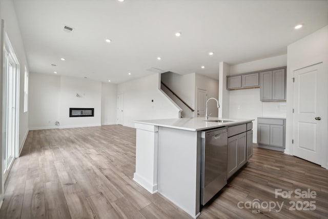 kitchen with a sink, dishwasher, gray cabinets, light wood-type flooring, and recessed lighting