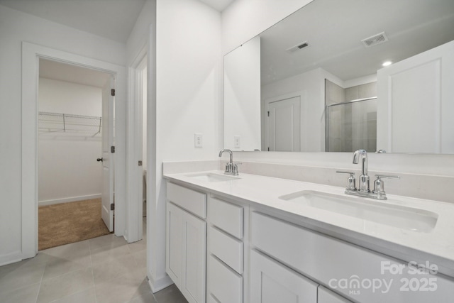 full bathroom with a shower stall, a spacious closet, double vanity, and tile patterned flooring