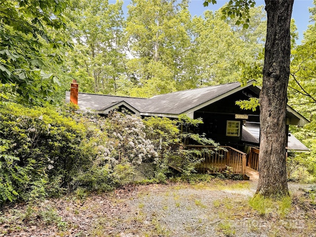 view of front of home featuring a chimney, a shingled roof, and a wooden deck