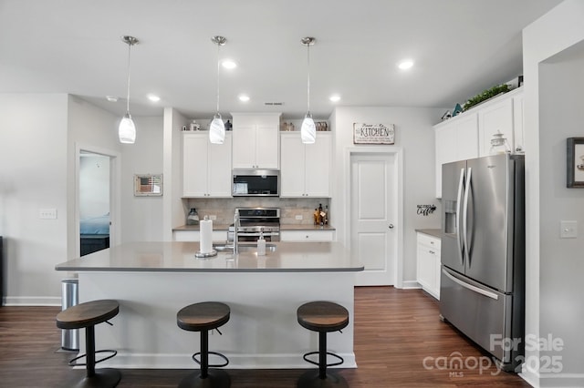 kitchen featuring appliances with stainless steel finishes, dark wood-style floors, decorative backsplash, a kitchen breakfast bar, and recessed lighting