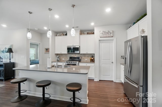 kitchen featuring stainless steel appliances, dark wood-type flooring, a sink, tasteful backsplash, and recessed lighting