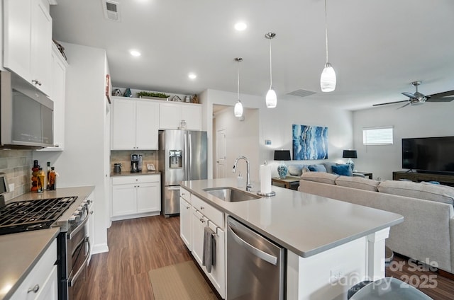 kitchen with appliances with stainless steel finishes, a sink, open floor plan, backsplash, and a ceiling fan