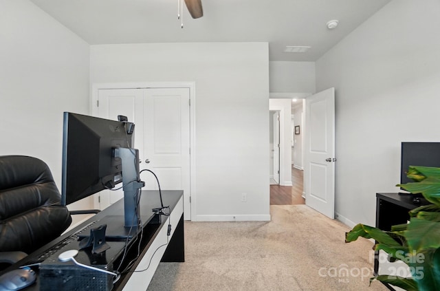 office featuring light colored carpet, ceiling fan, and baseboards