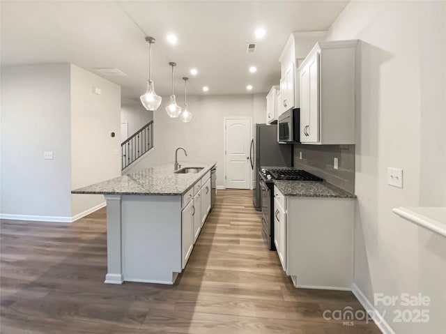 4105 Galloway Park Dr, Charlotte, NC 28262 - kitchen with stainless steel appliances, wood finished floors, a center island with sink, baseboards, and recessed lighting