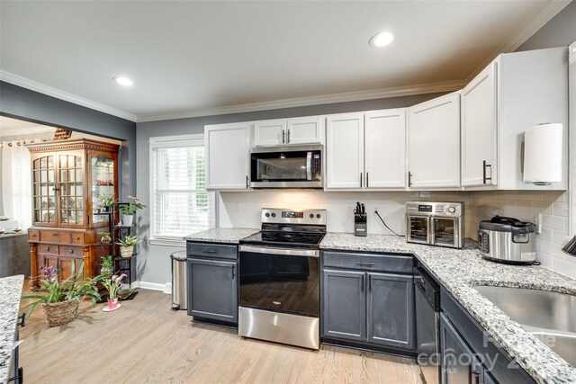 622 University Dr, Rock Hill, SC 29730 - kitchen featuring appliances with stainless steel finishes, white cabinets, light wood-style flooring, tasteful backsplash, and crown molding