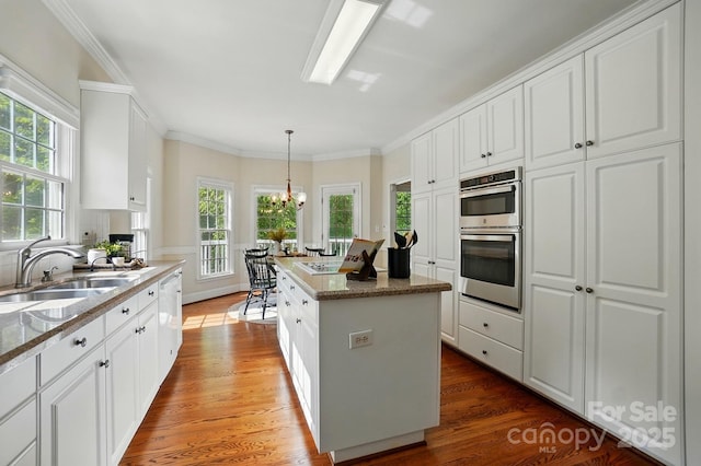 2725 Cotton Planter Ln, Charlotte, NC 28270 - kitchen featuring stainless steel double oven, wood finished floors, a sink, white cabinets, and crown molding