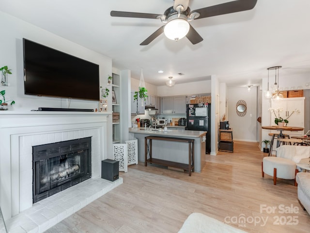 3308 Selwyn Farms Ln Unit 2, Charlotte, NC 28209 - living room featuring light wood-style flooring, a ceiling fan, a brick fireplace, and baseboards