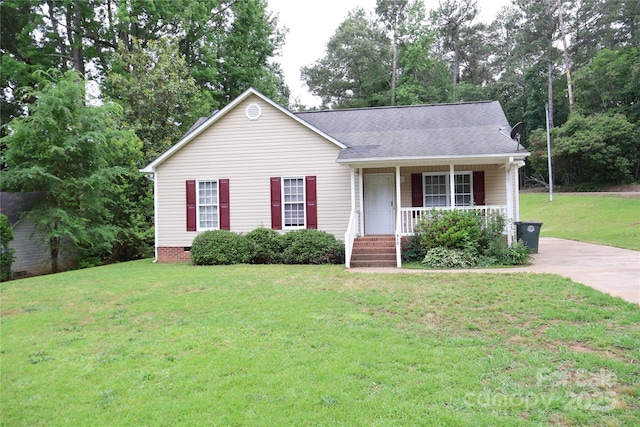view of front of property with a porch, a front yard, a shingled roof, and view of scattered trees