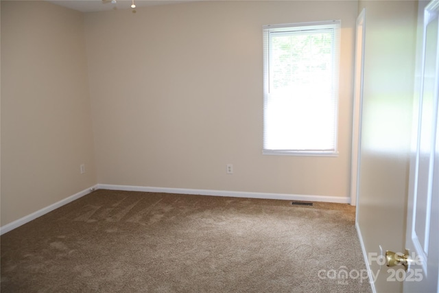 carpeted empty room featuring baseboards