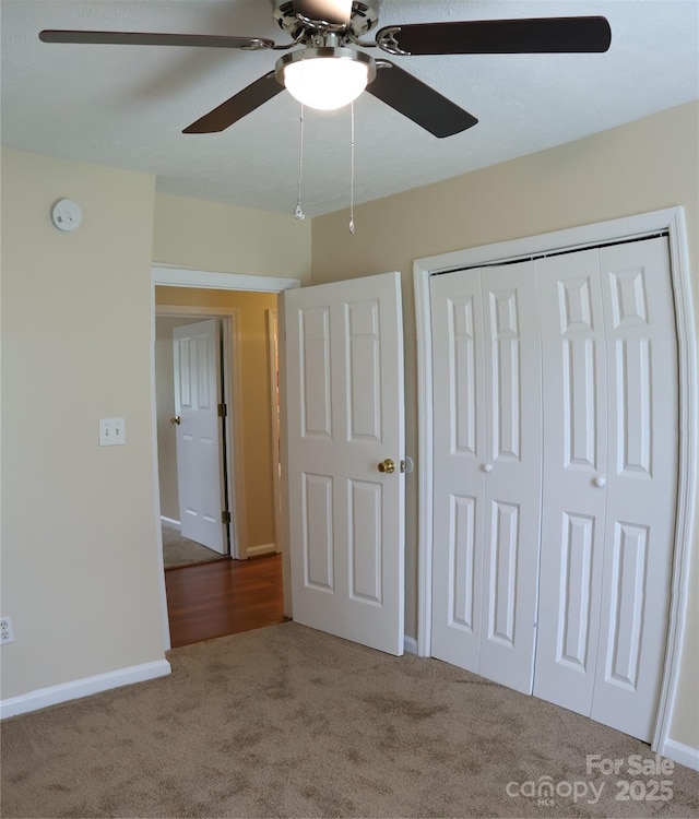 unfurnished bedroom featuring carpet flooring, a closet, a ceiling fan, and baseboards
