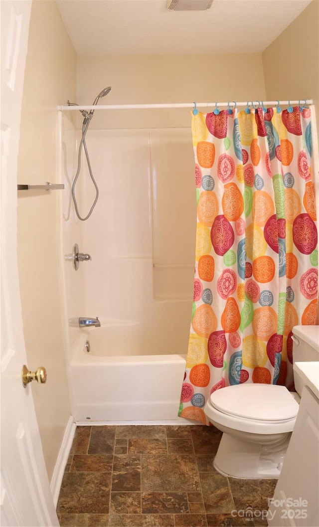 bathroom with stone finish flooring, shower / bath combo, vanity, and toilet