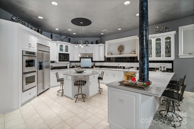 2971 Kaneland Ct, Rock Hill, SC 29732 - kitchen with built in appliances, a kitchen bar, decorative backsplash, glass insert cabinets, and recessed lighting