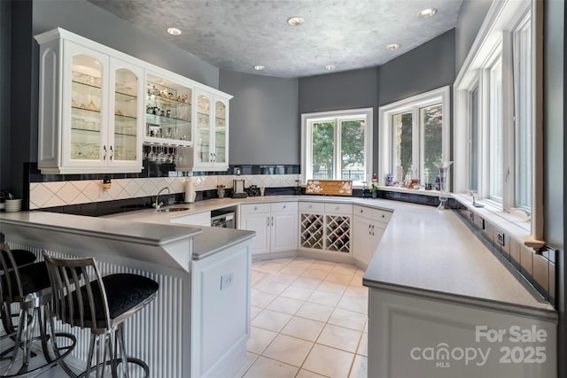 2971 Kaneland Ct, Rock Hill, SC 29732 - kitchen featuring a peninsula, a breakfast bar area, decorative backsplash, glass insert cabinets, and white cabinets