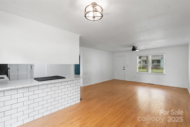 3103 Suggs St, Belmont, NC 28012 - unfurnished living room with a textured ceiling, a ceiling fan, light wood-style flooring, and baseboards
