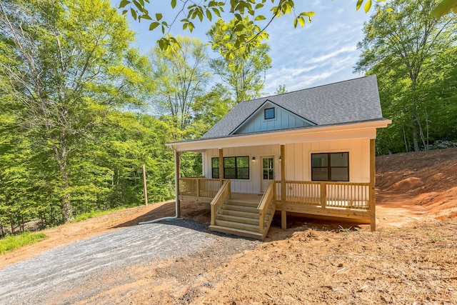 view of front facade featuring board and batten siding, roof with shingles, and a porch