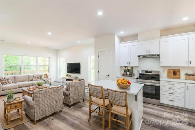 kitchen with stainless steel electric range, open floor plan, under cabinet range hood, white cabinetry, and recessed lighting