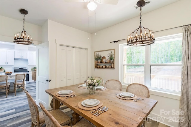 dining space with a chandelier, dark wood finished floors, and ceiling fan