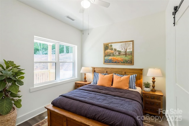 bedroom featuring wood finished floors, a barn door, baseboards, and a ceiling fan