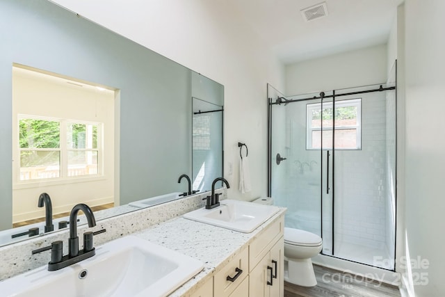 full bathroom featuring toilet, a stall shower, double vanity, and wood finished floors