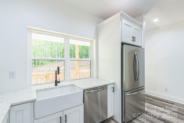 kitchen with stainless steel appliances, wood finished floors, a sink, plenty of natural light, and recessed lighting