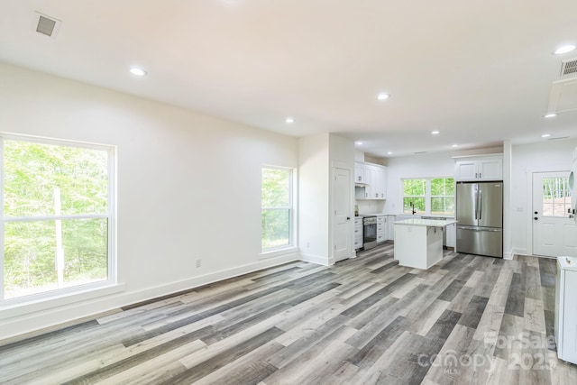 unfurnished living room featuring light wood-type flooring, recessed lighting, baseboards, and a sink