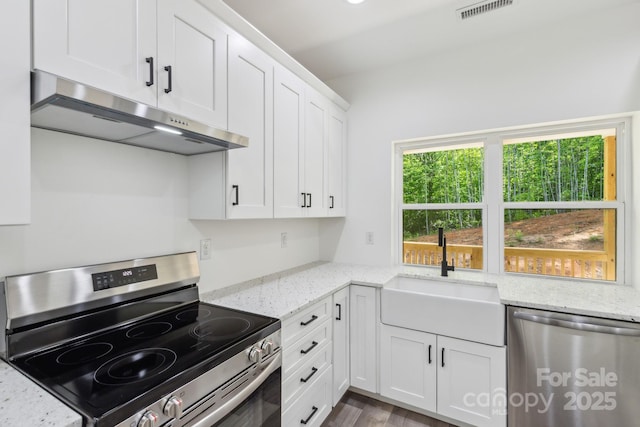 kitchen featuring stainless steel appliances, under cabinet range hood, a sink, white cabinets, and light stone countertops