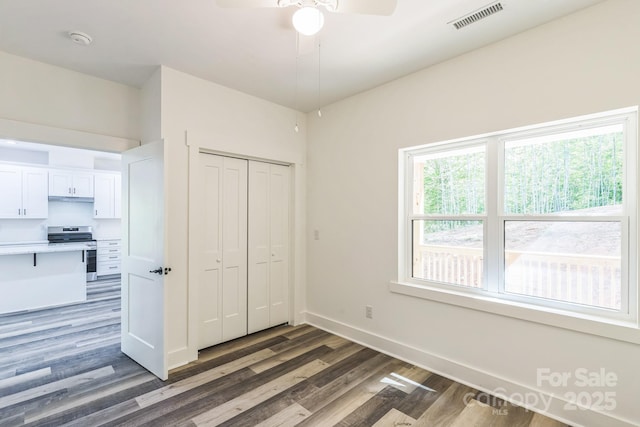 unfurnished bedroom featuring wood finished floors, baseboards, a closet, and ceiling fan
