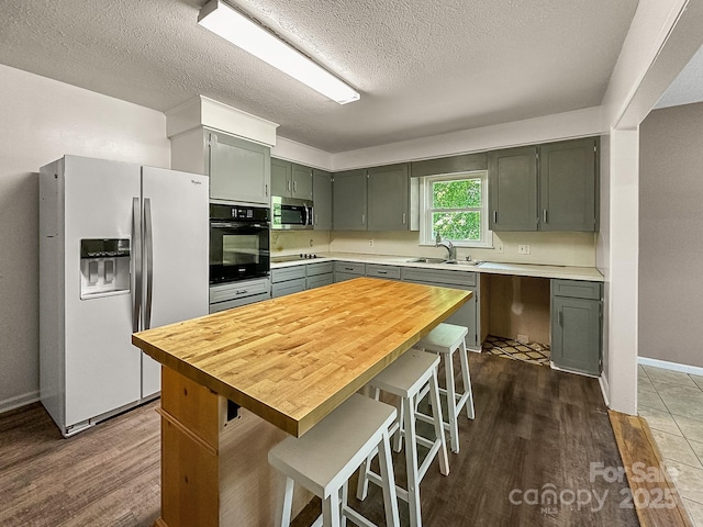 361 Settlemyer Rd, Morganton, NC 28655 - kitchen with black appliances, dark wood finished floors, a kitchen breakfast bar, a textured ceiling, and a sink